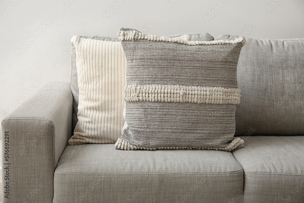 Decorative pillows on sofa near light wall, closeup