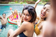 © Kawee - Asian women friend in bikini use mobile phone taking a photo at a pool.