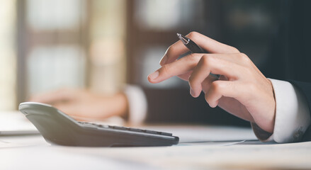 Aufkleber - Businessman calculating figures in company financial documents with a calculator,analysis of company financial data,Planning to assess and review budgets,concept of finance and investment.