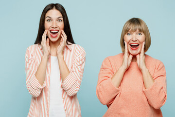 Elder parent mom with young adult daughter two women together wear casual clothes scream share hot news about sales discount with hand near mouth isolated on plain blue background. Family day concept