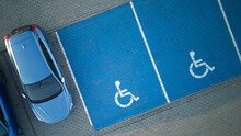 Outdoor car parking with handicapped symbol icon. Parking places reserved for disabled person. Aerial drone view