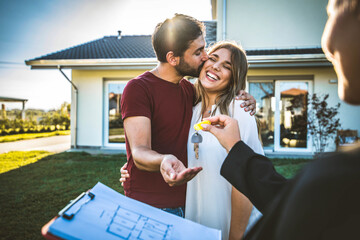 Happy millennial couple receiving keys from realtor, purchasing real estate - Family meeting with real estate agent - New house and real estate concept