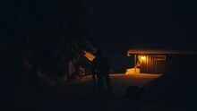 Silhouette Of A Man And His Pet Dog Outside The House On A Winter Night. Wide