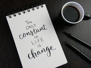 Wall Mural - THE ONLY CONSTANT IN LIFE IS CHANGE lettering in notebook with cup of coffee and pens on black wooden desk