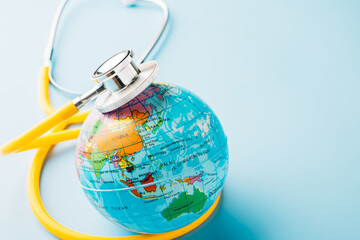 World Health Day. Top view yellow doctor stethoscope wrapped around world globe isolated on pastel blue background with copy space for text, Save world day, Health care and medical concept