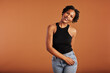 © Flamingo Images - Smiling black woman standing in front of an orange background