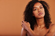 © Flamingo Images - Young black woman with bare shoulders posing on an orange background