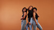 © Flamingo Images - Laughing group of women standing in front of an orange background