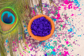 Colorful powders for holi on clay pots on occasion of indian festival of colors. happy holi theme shot with peacock feathers. copy space for text.