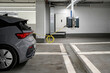 A gray electric car is charging in an underground parking. The concept of ecological energy systems.