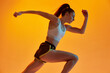 © master1305 - Speed up. Young girl, professional runner athlete in uniform training, running over orange studio background in neon light. Concept of sportive lifestyle, health, endurance, action and motion. Ad