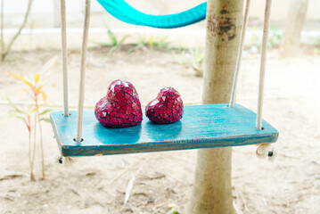 Close up of two red hearts on wooden table swing.