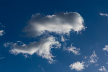 White fleecy clouds on a sunny day with clear blue sky over Germany. Symbol of good weather called “Cumulus humilis“ in meteorology science. Small condensed water particles and drops reflecting light.