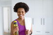 © Wavebreak Media - Portrait of smiling mid adult african american woman with water bottle and napkin at home