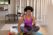 © Wavebreak Media - Mid adult african american woman using smart phone while practicing yoga at home