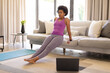 © Wavebreak Media - Determined mid adult african american woman practicing online yoga in living room at home