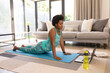 © Wavebreak Media - Mid adult african american woman in sportswear practicing online yoga at home