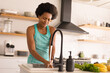 © Wavebreak Media - Mid adult african american woman washing hands while preparing food at home