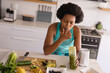 © Wavebreak Media - Mid adult african american woman licking finger while drinking healthy juice in kitchen at home