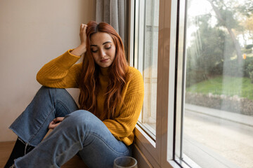 Sad woman drinking wine. Young redhead woman drinking wine at home, she is sad and disappointed because of a heartbreak.