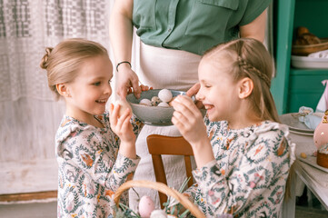 Wall Mural - easter holiday time in spring season. happy family candid little kids sisters girls together mother mom have fun at home, traditional shackling, jarping or dumping with eggs. religious tradition