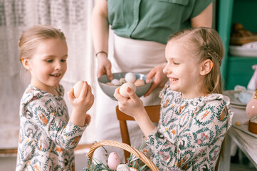 Wall Mural - easter holiday time in spring season. happy family candid little kids sisters girls together mother mom have fun at home, traditional shackling, jarping or dumping with eggs. religious tradition