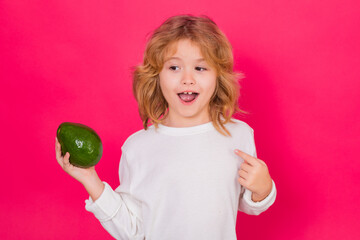 Wall Mural - Kid hold red avocado in studio. Studio portrait of cute child with avocado isolated on red background.