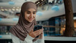 © Yuliia - Young arabian latina woman student girl look at mobile screen shopping online buying goods in virtual store use phone digital apps read blog news female businesswoman shopper check internet discounts