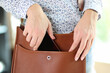 Woman putting smartphone in brown leather crossbody