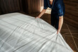 © Dusan Petkovic - Close up of a chambermaid making bedsheets on a bed in a hotel room.