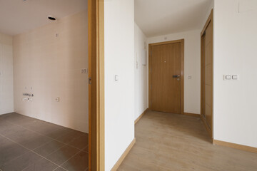 Wall Mural - Entrance hall of an empty house with an oak wood access door to match the rest of the doors, a built-in wardrobe with sliding doors and stoneware floors and laminated flooring