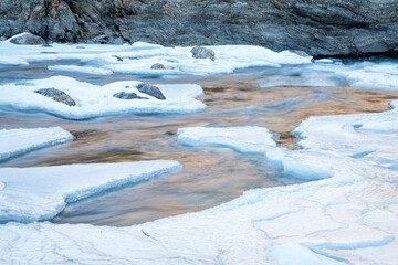 Wall Mural - partially frozen Poudre River in northern Colorado - ice, water and rock abstract