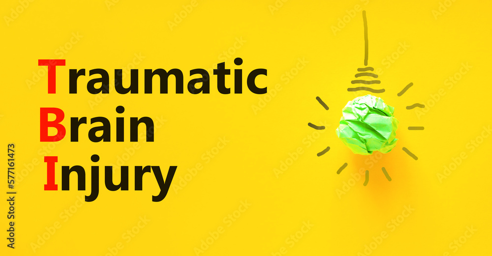 TBI traumatic brain injury symbol. Concept words TBI traumatic brain injury on paper on beautiful yellow background. Green light bulb icon. Medical and TBI traumatic brain injury concept. Copy space.