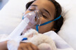 © Wavebreak Media - Sick biracial girl sleeping with oxygen mask and teddy bear on hospital bed