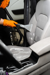 Wall Mural - Car cleaner is extracting dirt from car seat using dry cleaning extractor machine. Cleaning textile seats in car interior using extractor machine for dry clean.