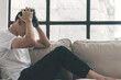 © kaew6566 - Lonely tired asian man holding hands own headache worry problem sitting on sofa at home. Unemployed people hopeless sadness alone beside window sitting on couch thoughtful problem life. Trouble life.