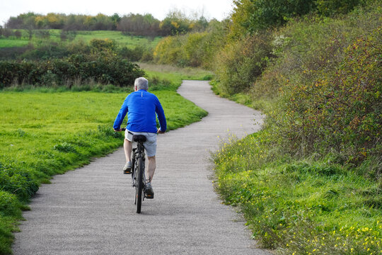 elderly cyclist on a path in autumn park