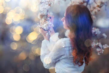 spring portrait of an adult happy woman in a blooming garden, sun rays and glare, april flowers girl