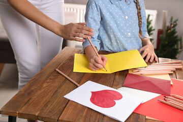 Wall Mural - Little girl with her mother making beautiful greeting card at home, closeup