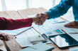 © Ratirath - Close up bookkeepers working with balance sheet to analyze problems and find solutions to bringing develop business organization and company's stock market system. Shaking hands after agreement