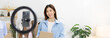 © Puwasit Inyavileart - Woman with a social media influence is greeting the audience for recording vlog video live streaming, Lift the postage box during the live show to confirm the customer's order, Online fashion clothing