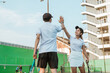 © Odua Images - Mixed doubles players high-five each other celebrating success while playing on the tennis court