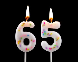 White decorated burning birthday candles on black background. Number 65.