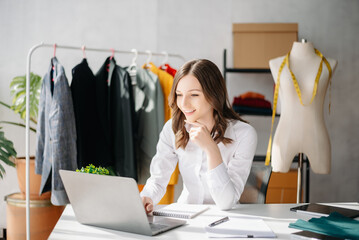 Diverse female fashion designers at work with tailor centimeters on necks and holds tablet and smartphone.