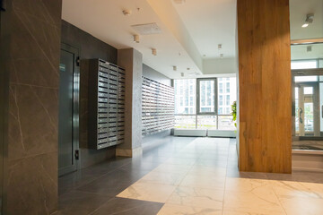 Hall of modern multifamily building. Entrance, metal mailboxes a lot. Multistory residential building hall.