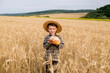 © volody10 - A little boy in a hat is holding bread while standing in a wheat field. Agriculture, farming