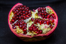 Red Pomegranate Lies On A Black Background With Red Grains