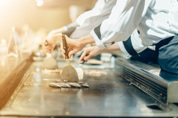 Wall Mural - Hand of man take cooking of meat with vegetable grill, Chef cooking wagyu beef in Japanese teppanyaki restaurant