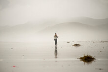 A woman feels for rain on a cloudy day at the beach at Morro Bay, Calif.