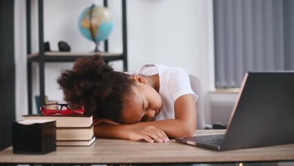 Wall Mural - Sleeping by leaning on the table. Feeling tired. Cute female african american student child is sitting by the laptop.